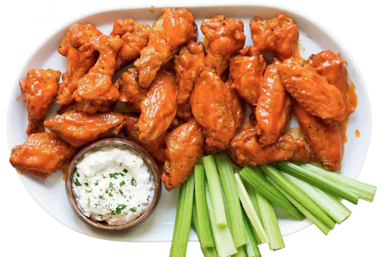 Buffalo chicken wings platter with celery sticks and blue cheese dip on white plate